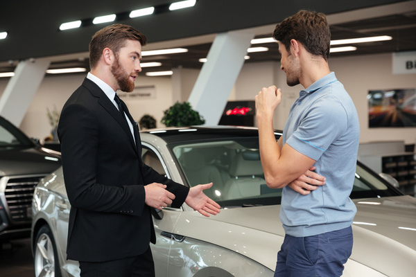 a salesman showcasing a car to a potential buyer