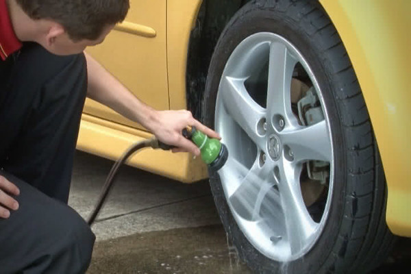 Man rinsing the car's wheel