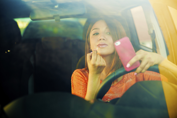 Woman applying lipstick in the car